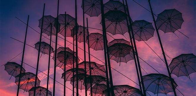 Looking up on umbrellas stuck on wires at dusk